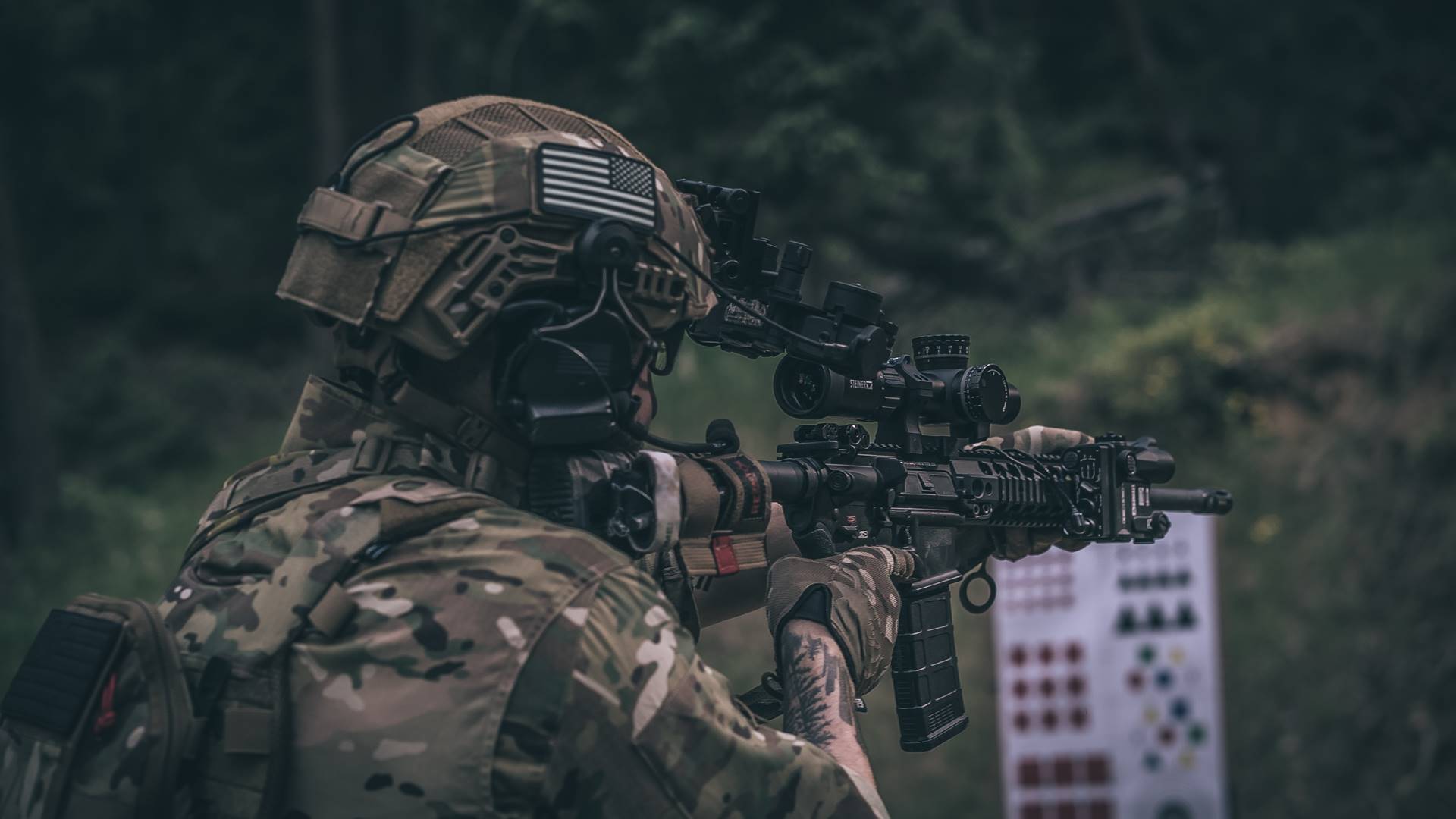 Person in helmet and camouflage pointing a gun 