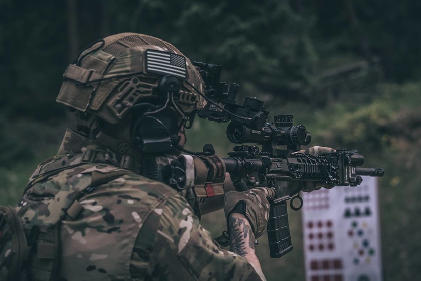 Person in helmet and camouflage pointing a gun