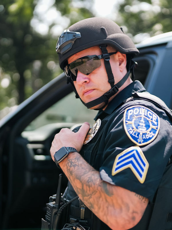 Poliziotto con elmetto nero che tiene in mano la radio