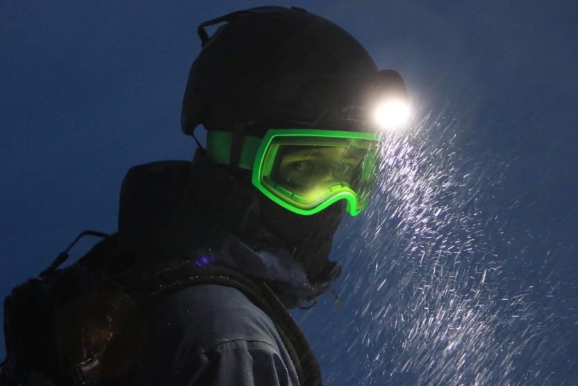 Man wearing headlight and helmet with neon green ski goggles