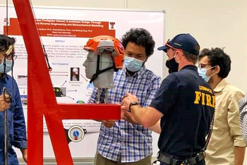 People wearing masks looking at a display helmet