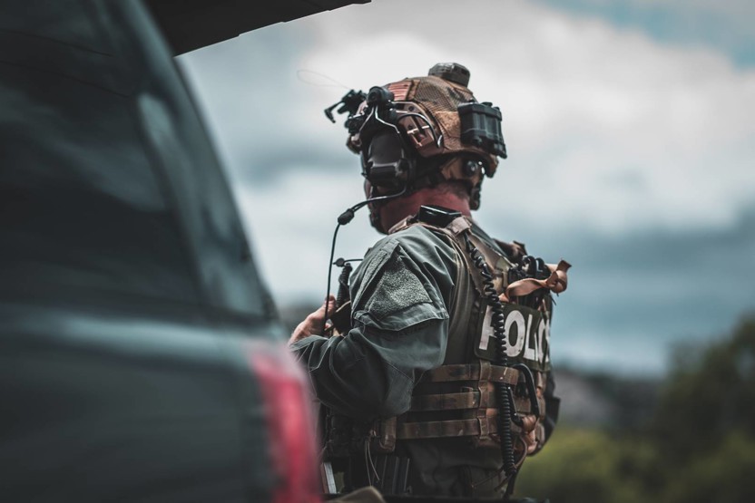 Man wearing camo police vest and helmet