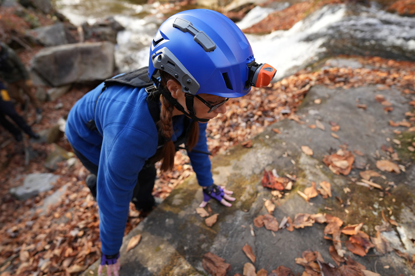 Search and rescue professional in a Team Wendy SAR helmet navigating difficult terrain in the forest