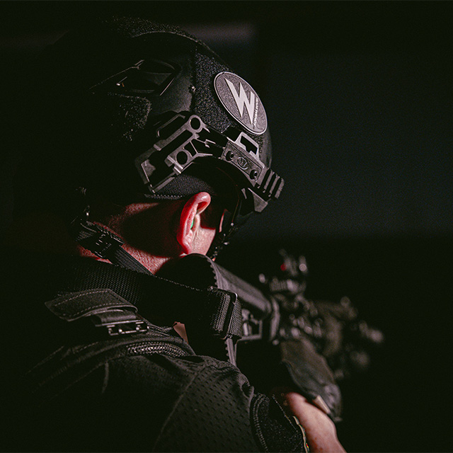 Image from back angle of man in helmet pointing a gun