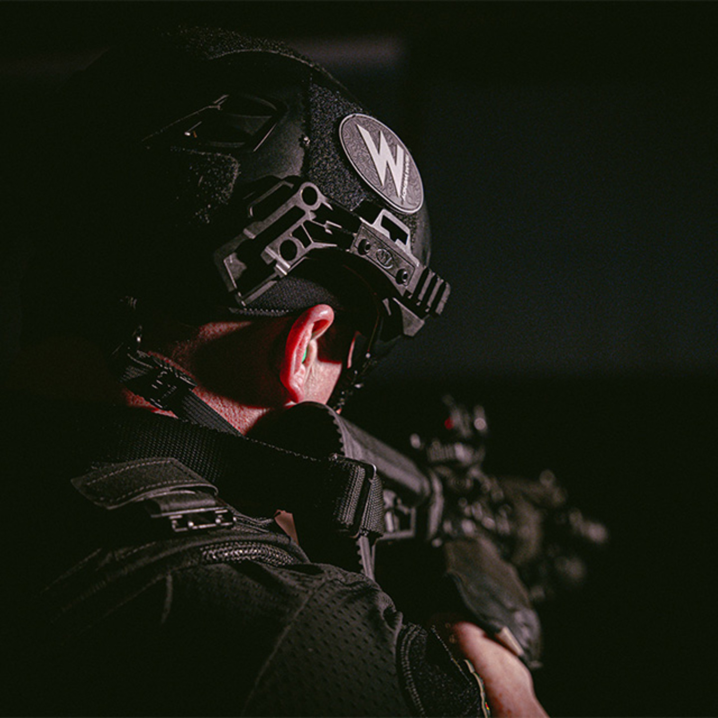 Image from back angle of man in helmet pointing a gun