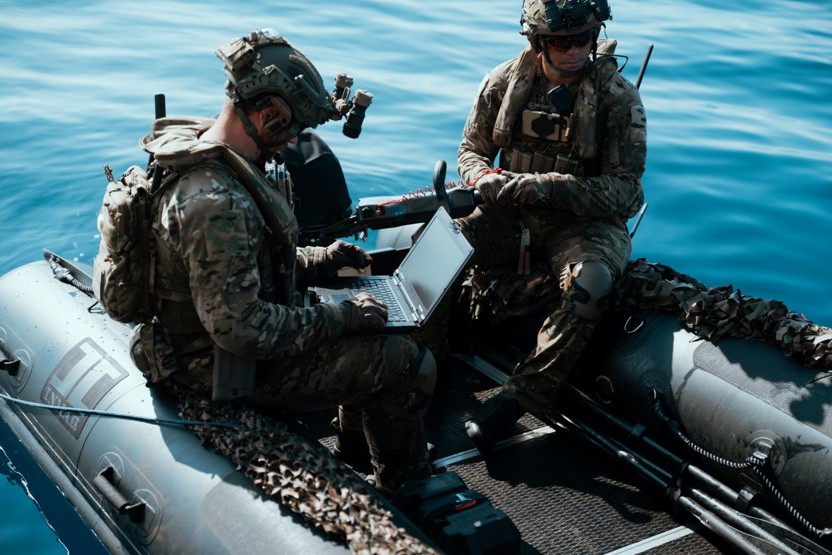 Soldiers in a boat checking data on a laptop and wearing Team Wendy RIFLETECH rifle-rated ballistic helmets