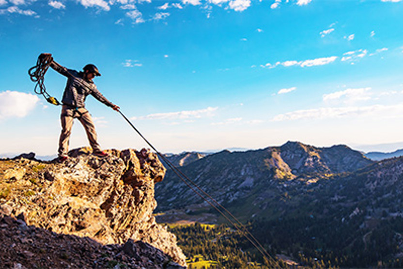 Man on cliff using rope