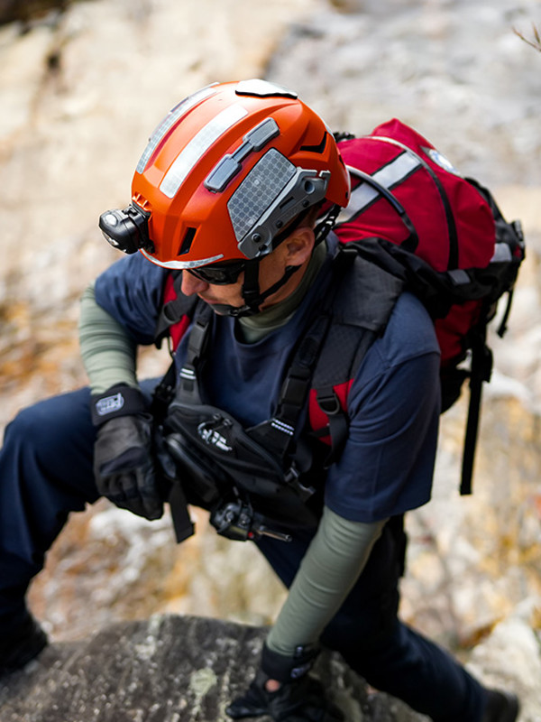 Man in orange helmet climbing a rockface