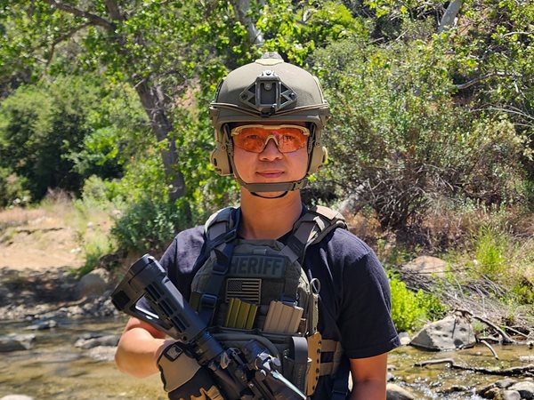 Man in protective eyewear, helmet, and holding a gun