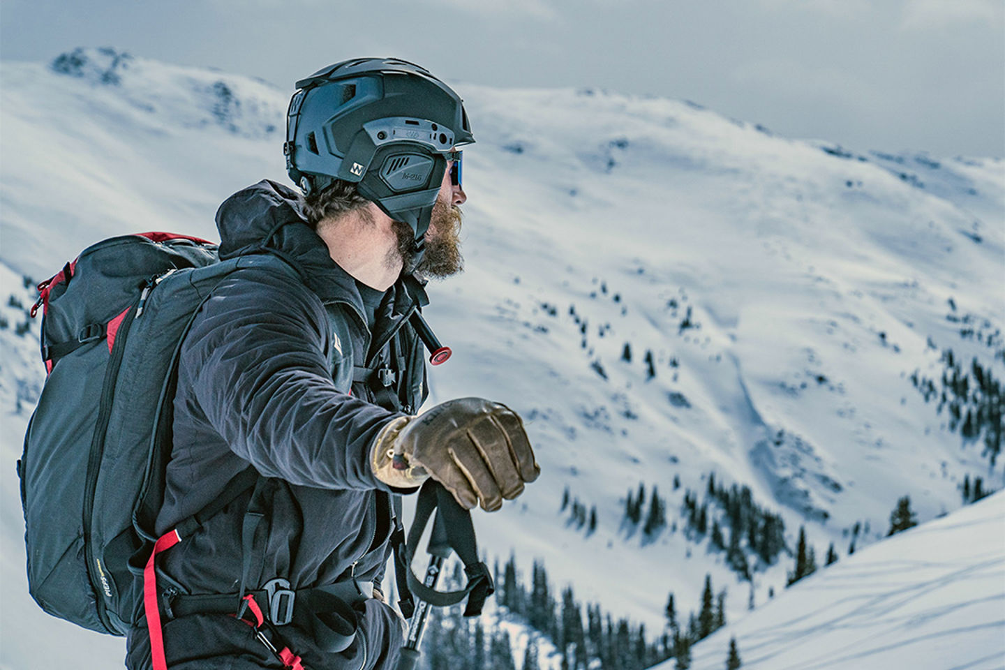 Cordillera cubierta de nieve y un hombre con mochila, casco y abrigo