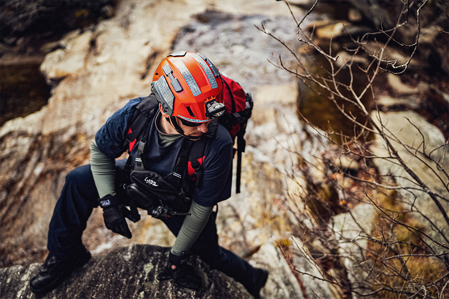 Man in orange helmet climbing a rockface