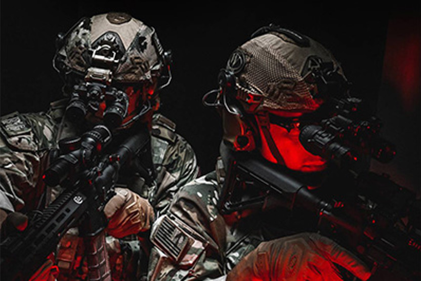 Men in camo and helmets using guns in the dark