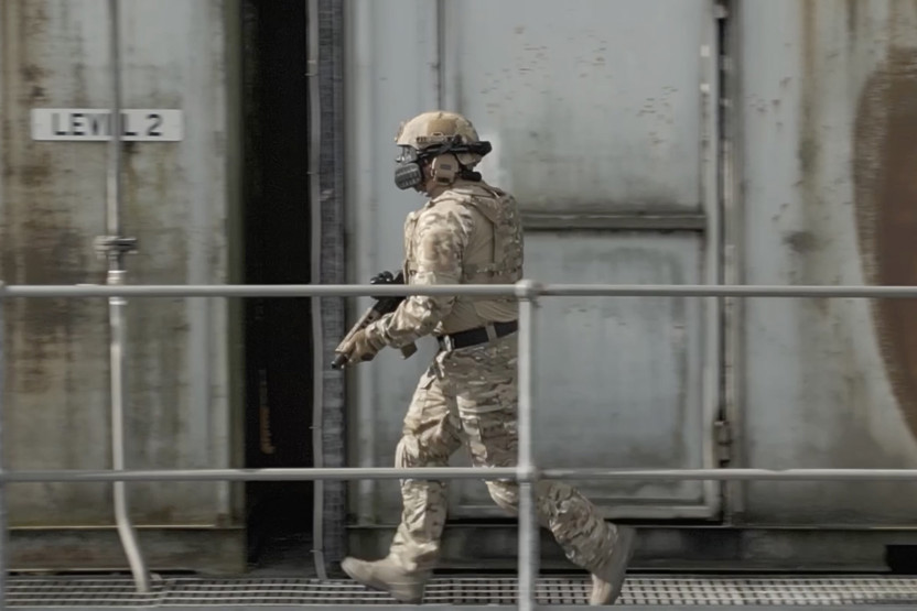 Soldier holding a gun walking next to a railing