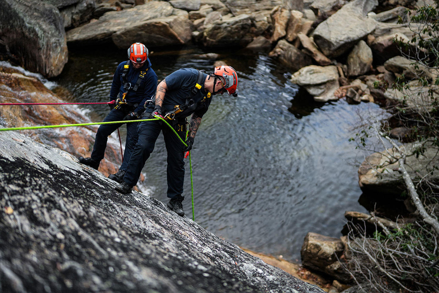 Deux personnes portant des casques descendent en rappel le long d'une paroi rocheuse