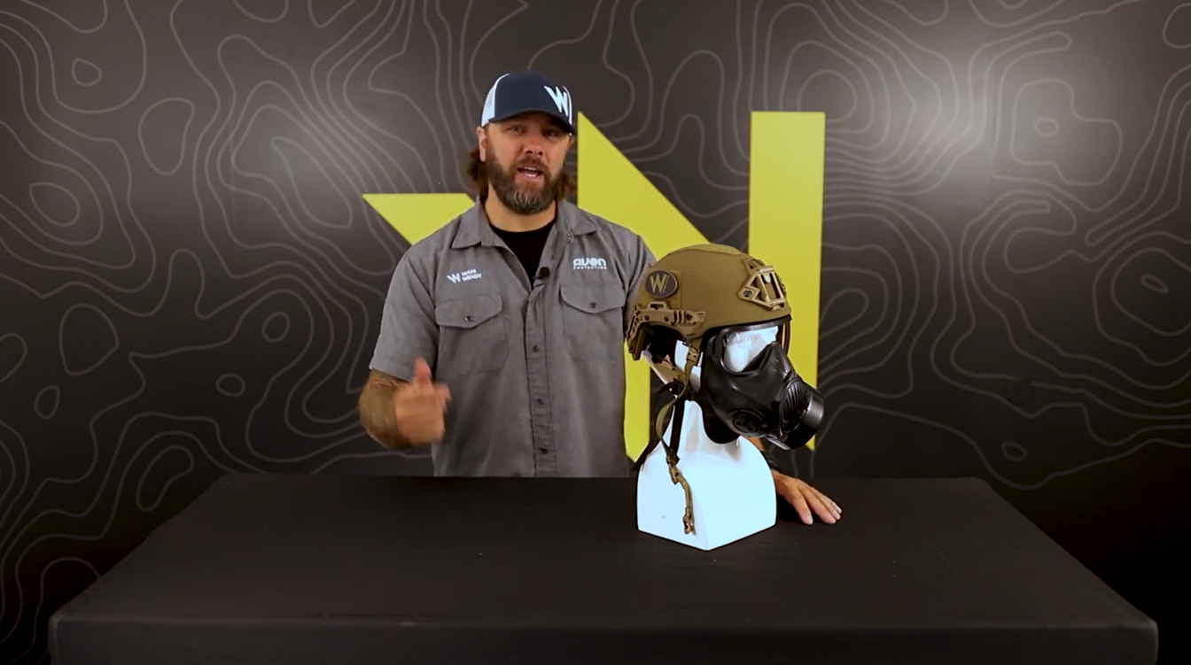 Team Wendy employee standing in front of a bust wearing a Team Wendy EXFIL ballistic helmet and an Avon Protection C50 Respirator