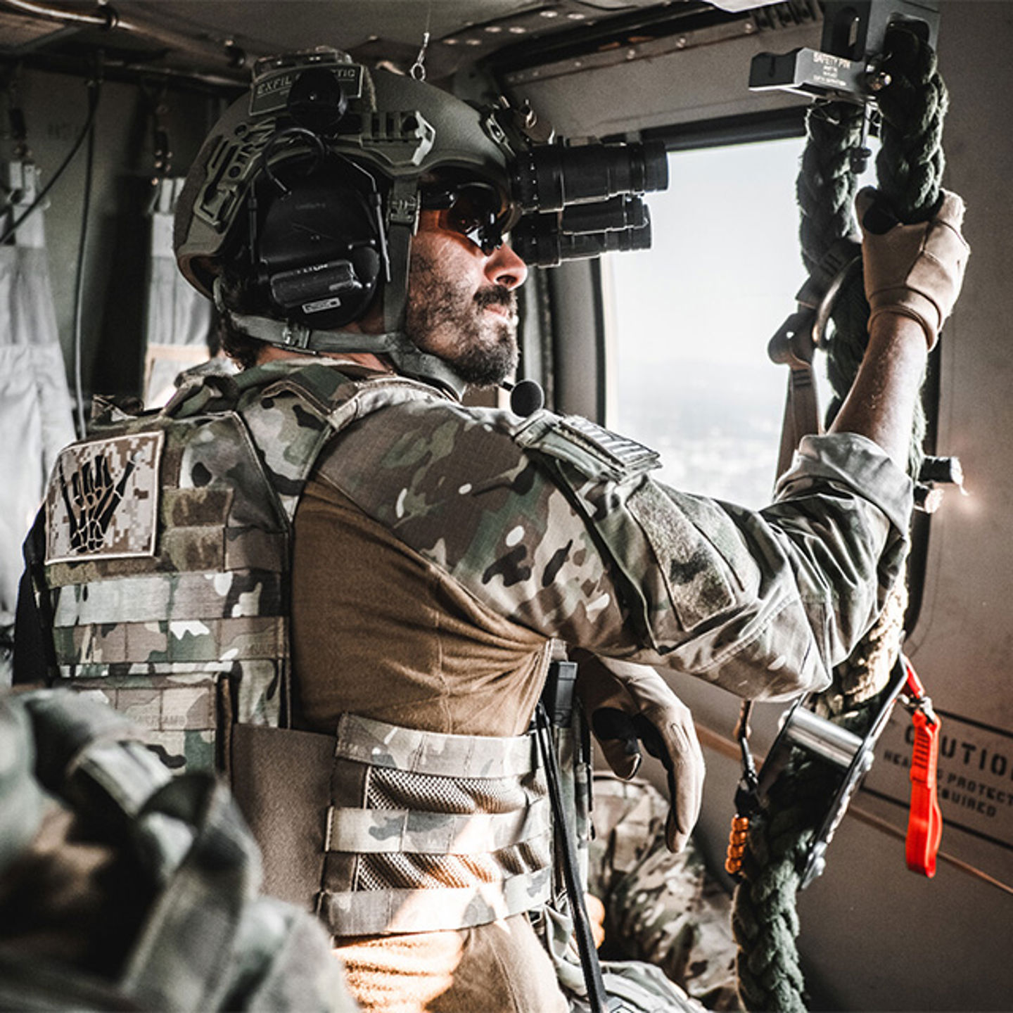 Un homme vêtu d'une tenue de camouflage verte et d'un casque, agrippé à une corde