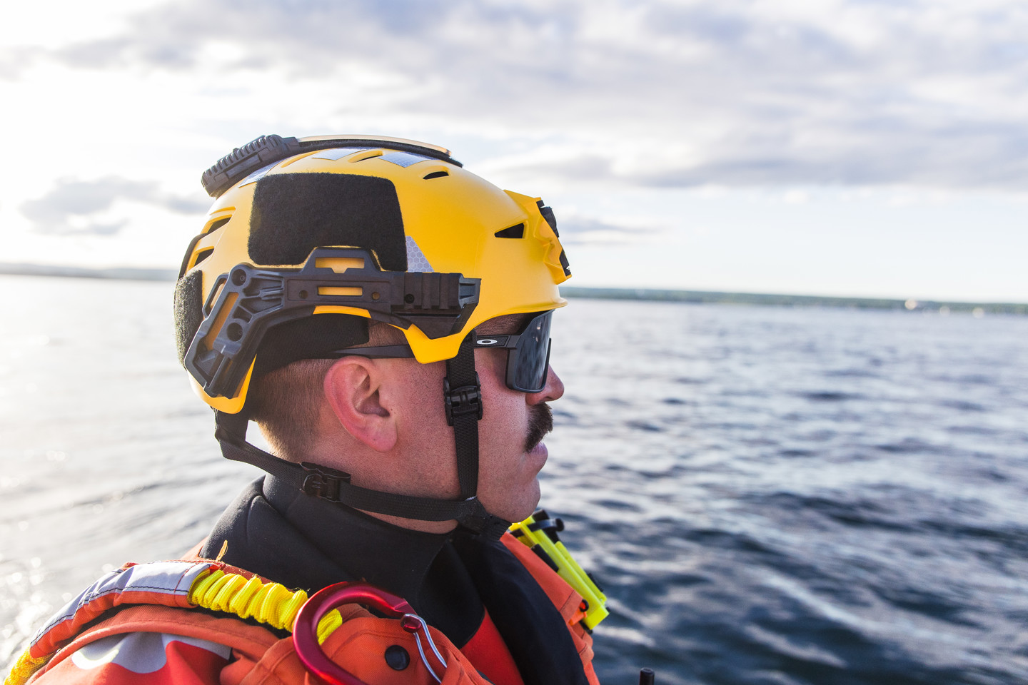 US Coast Guard on a boat surveying the area wearing a yellow Team Wendy EXFIL Rescuer helmet