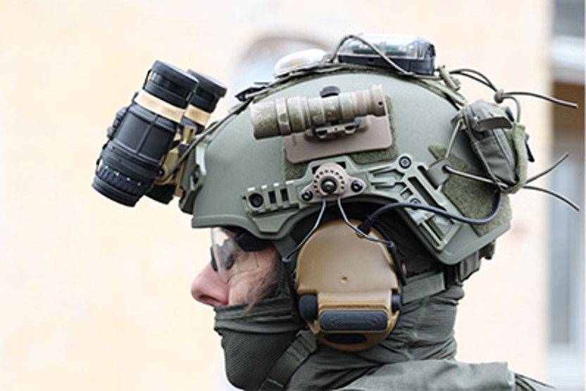 Man with green helmet on and helmet accessories