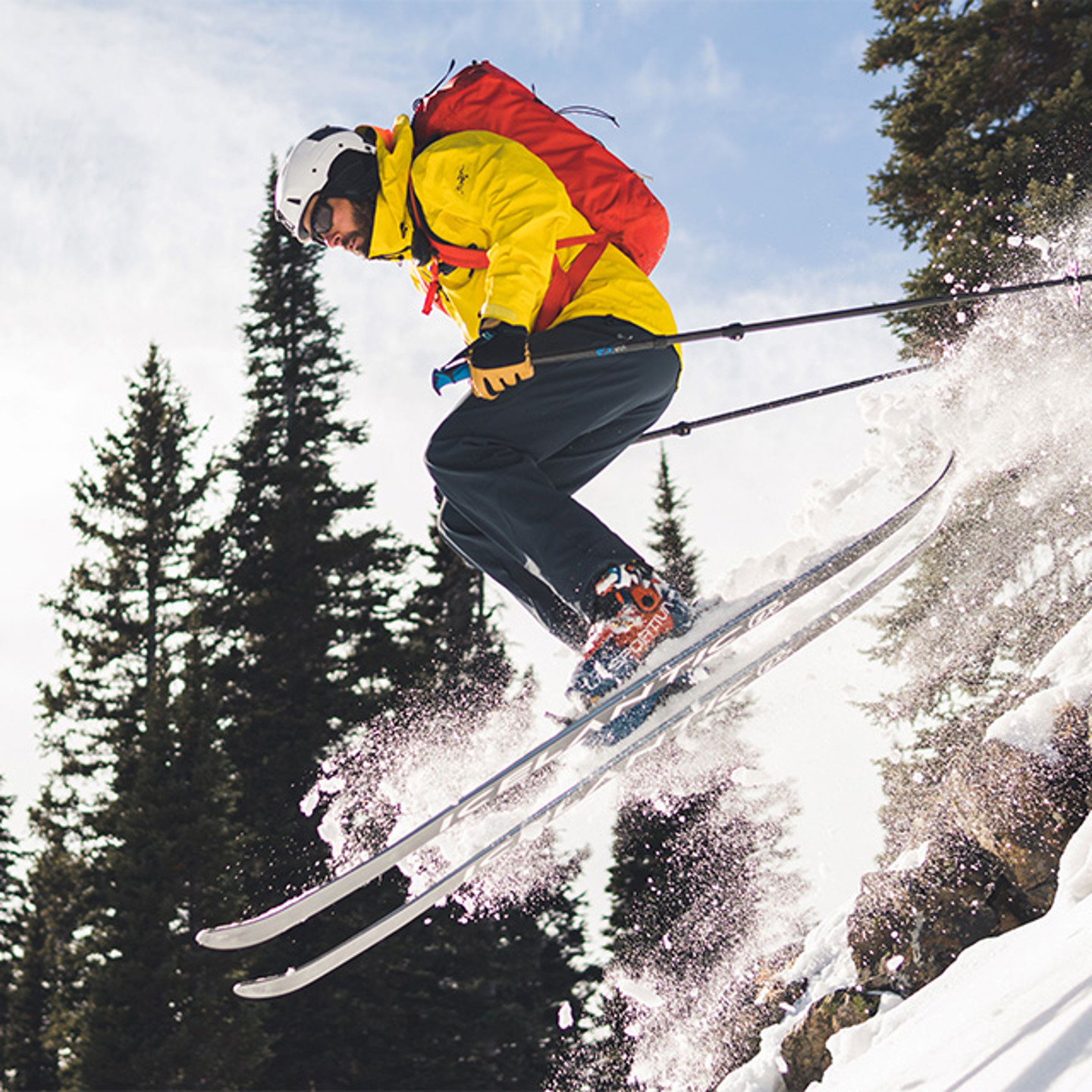 Man in yellow jacket and white helmet skiing