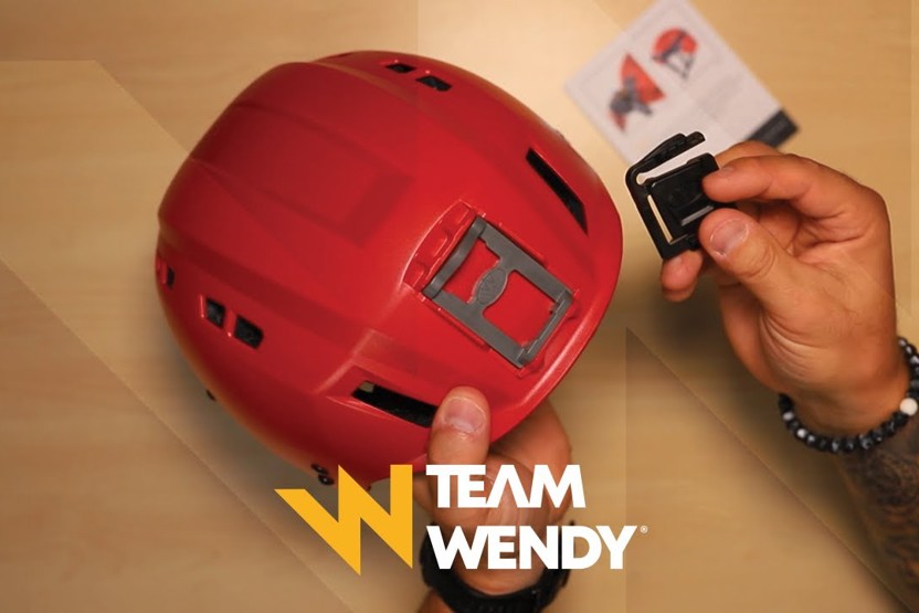 Person installing a shroud headlight adapter to a red Team Wendy SAR Backcountry helmet