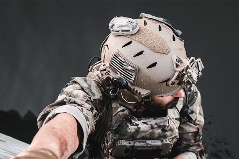 Man in camo climbing and wearing a helmet